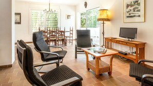 A spacious living area with a television, a dining table, and several chairs.