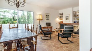 A dining area with a large wooden table and chairs, a television, and a fireplace.