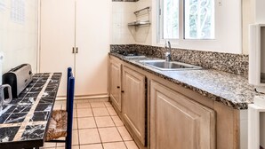 A small kitchen with a granite countertop, a sink, and a window above the sink.