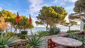 A patio with a round table and chairs, surrounded by various plants and trees, overlooking a body of water. - Les Tonyines 68 - apartment with views and terrace (Llança)
