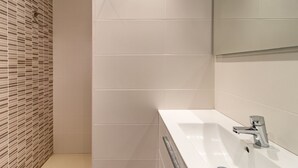 A bathroom with a white sink, a mirror, and a tiled wall with a patterned section. - Les Tonyines 68 - apartment with views and terrace (Llança)