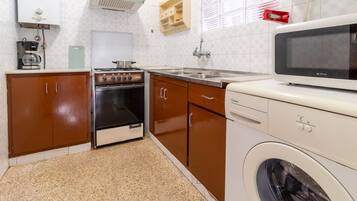 Een koelkast, een magnetron, een oven, kookgerei, borden en bestek