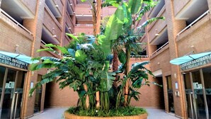 Ein mehrstöckiges Gebäude mit einem zentralen Atrium und einer üppigen Pflanzeninszenierung.