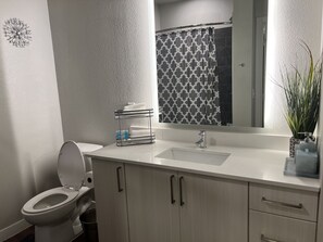 Ein modernes Badezimmer mit Toilette, Waschbecken und Spiegel.