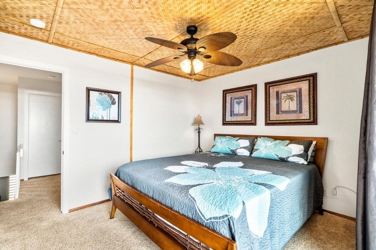 A bedroom with a wooden bed, a ceiling fan, and framed pictures on the wall.