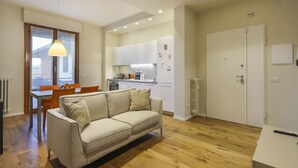 En kompakt bolig med et tekøkken, en sofa, et spisebord og et stort vindue.