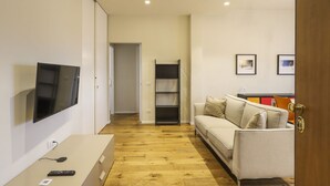 En moderne stue med et fladskærms-tv, en sofa, et sofabord og en bogreol.