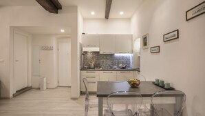 A modern kitchen with white cabinets, a tiled backsplash, and a dining area with a table and chairs. - Florence Little Suite - Sweet Dreams in Florence (Firenze)