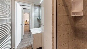 A narrow hallway leading to a bathroom with a shower, a sink, and a towel rack. - Serenity - Sweet Dreams in Florence (Firenze)