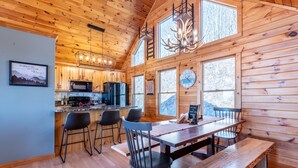 A wooden cabin interior with a kitchen, dining area, and large windows. - Private Sunset-view Cabin • Hot Tub • Sauna • Game Room • Dog-friendly (Blairsville)