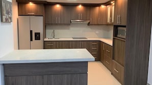 Une cuisine moderne avec des meubles de couleur sombre, un îlot central et des appareils électroménagers intégrés.