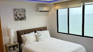 Une chambre à coucher comprenant un lit, une table de chevet, un appareil de climatisation, une fenêtre avec vue et un plafond doté d’un éclairage bleu.