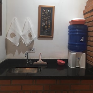 Kitchen area with a black countertop, framed kitchen utensil display, and a water dispenser.