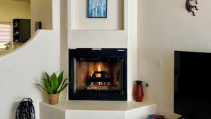 A living room with a fireplace, a television, and a decorative wall piece.