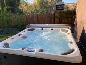 Un jacuzzi con chorros, rodeado por una cerca de madera y un jardín.