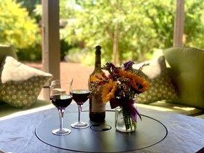 Una mesa con una botella de vino, dos copas de vino y un florero con flores.