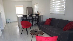 Ein modernes Wohnzimmer mit einem grauen Sofa, roten Sesseln und einem kleinen Couchtisch.