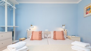 Un dormitorio con una cama doble, dos mesitas de noche, un aparador y un tendedero de pared.
