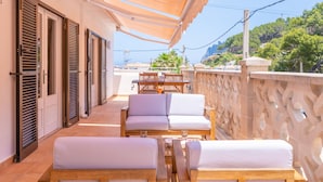Una terraza con mobiliario de madera, una mesa y un sofá.