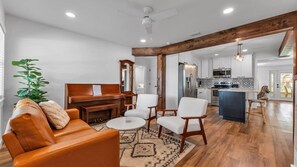 A modern living room with a piano, sofa, chairs, and a dining area with a kitchen in the background. - Modern Boho Retreat with Piano. Fenced and Gated in Central Florida! (Lakeland)