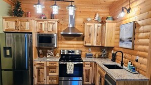 A wooden-paneled kitchen with stainless steel appliances, a central island, and pendant lighting.