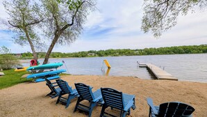 A lakeside area with chairs and canoes, a dock, and a ladder.
