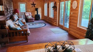 A cozy cabin interior with a fireplace, a sofa, a chair, and a dining table.
