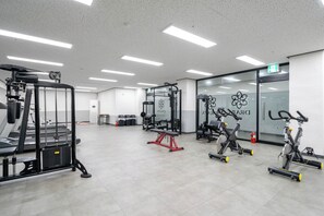 Un gimnasio con equipo de ejercicio, una banca y una pared con un logotipo.