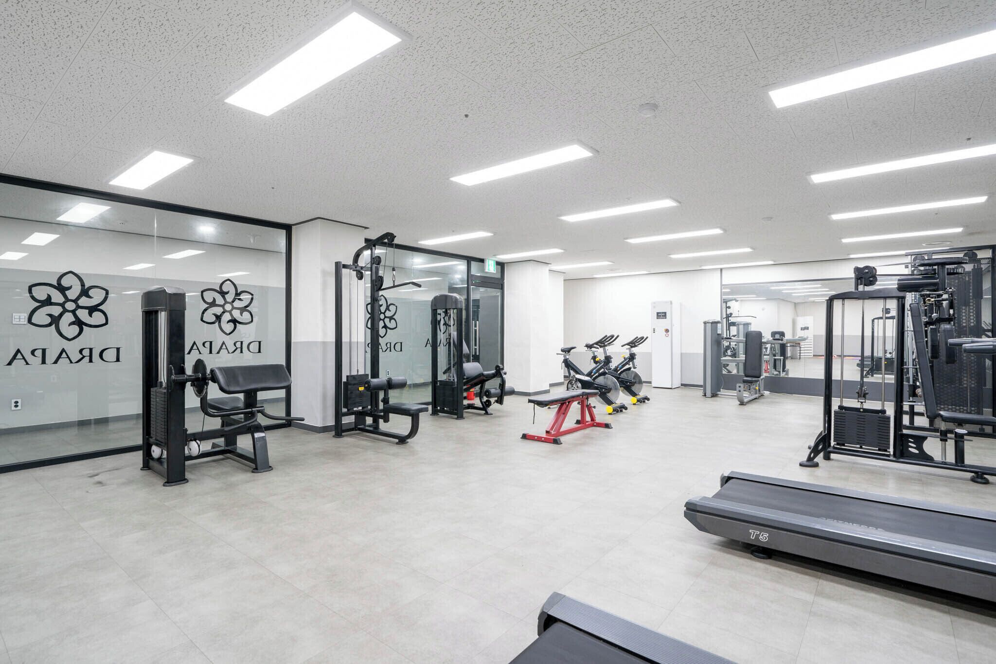 A gym with exercise equipment, a treadmill, and mirrored walls.