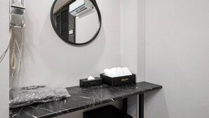 A bathroom with a hairdryer, a mirror, a towel box, and a tissue box. - Cheonan DRAPA Hotel (Cheonan)