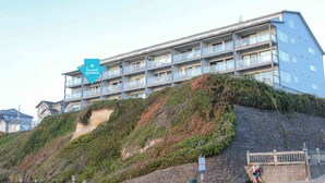 Un hotel de varios pisos con balcones, situado en una colina con vegetación.