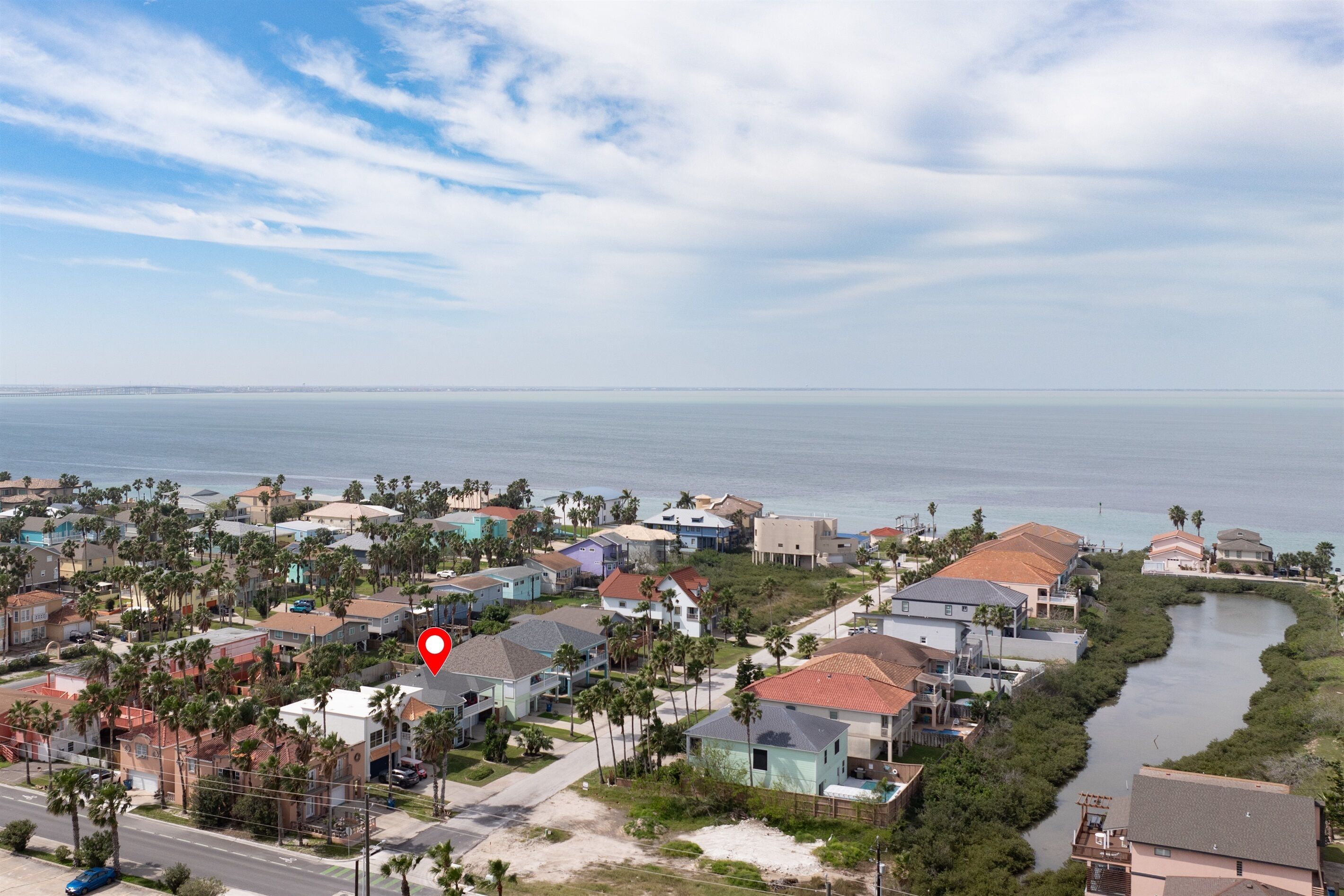 A coastal residential area with houses, palm trees, and a river.