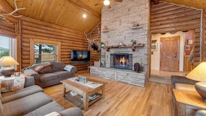 A log cabin interior with a stone fireplace, wooden furniture, and a television. - Cozy Custom Cabin In The Pines-Williams AZ (Williams)