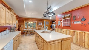 A kitchen with wooden cabinets, a central island, and a red accent wall. - Cozy Custom Cabin In The Pines-Williams AZ (Williams)