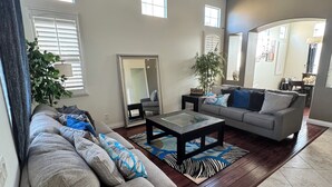 A spacious living room with a grey sofa, a coffee table, and a large mirror. - Peaceful Home Away! (San Jacinto)