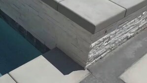 A rectangular hot tub with a stone border, surrounded by a concrete deck. - Peaceful Home Away! (San Jacinto)
