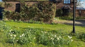 A traditional brick house with a sloped roof, a chimney, and a well-maintained garden with white flowers. - Cosy Rural Retreat, Sleeps 3 & PetFriendly (Pewsey)