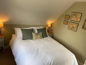 A neatly made bed with white bedding and green pillows, two bedside lamps, and framed artwork on the wall. - Cosy Rural Retreat, Sleeps 3 & PetFriendly (Pewsey)