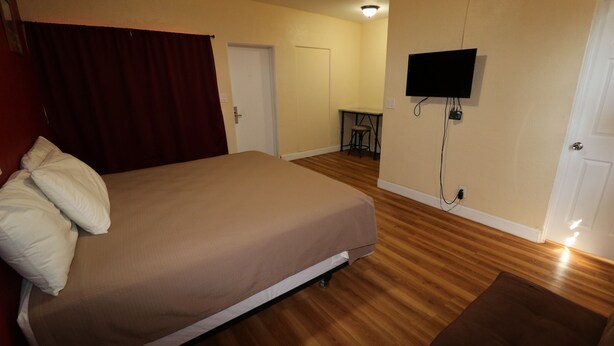Ein Schlafzimmer mit einem Bett, einem Schreibtisch, einem Stuhl und einem Fernseher.