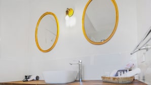 A bathroom with two oval mirrors, a white sink, and a wooden vanity. - Coast Motel Eden (Eden)