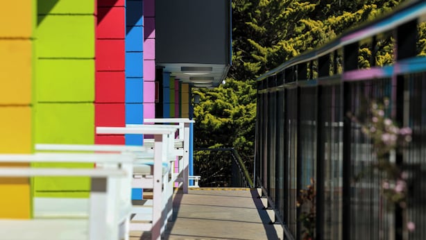A colorful building with a wooden deck and a metal railing. - Coast Motel Eden (Eden)