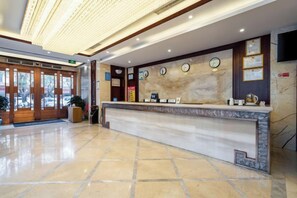 A hotel reception area with a marble counter, clocks, and a television on the wall. - Suiton Plus By Paxton Linzhi (Nyingchi)