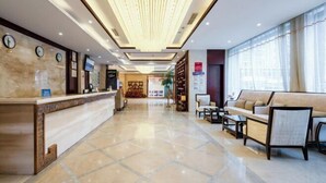 A hotel lobby with a reception desk, seating area, and a large window.