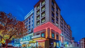 A multi-story hotel with illuminated signage and a prominent corner entrance.