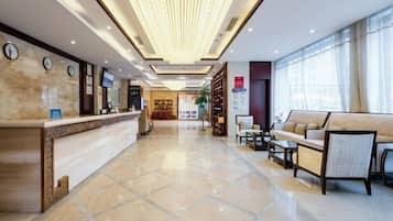 A hotel lobby with a reception desk, seating area, and a chandelier.