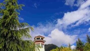 A tower with a red and white facade, surrounded by greenery and under a clear sky.