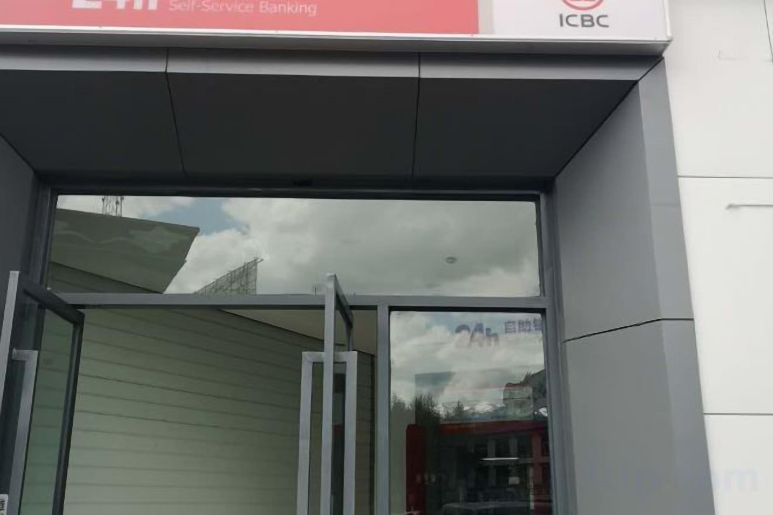 A bank entrance with a glass door and a sign indicating self-service banking.