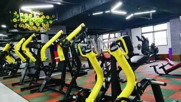 A gym with exercise equipment, including weight machines and cardio machines, arranged in rows.