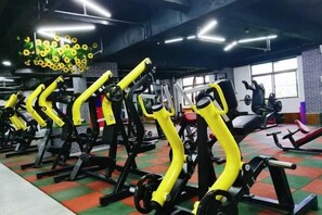 Un gimnasio con equipo de ejercicio, que incluye máquinas de pesas y máquinas de cardio, dispuestas en filas.