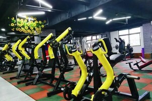 A gym with exercise equipment, including weight machines and cardio machines, arranged in rows.